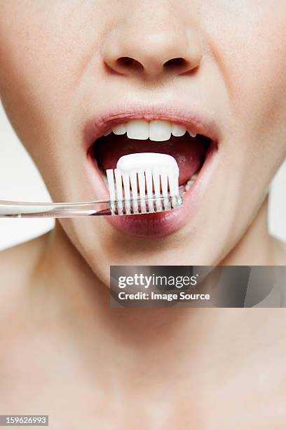 woman brushing teeth - toothpaste stock-fotos und bilder