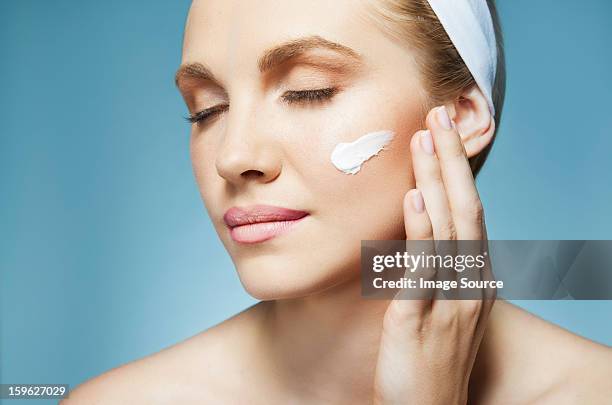 woman applying moisturiser - cheek - fotografias e filmes do acervo