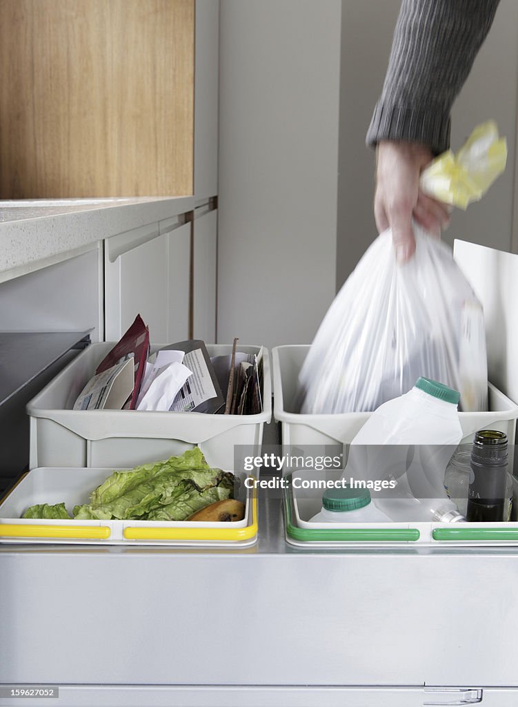 Person removing rubbish bag from waste and recycling drawer