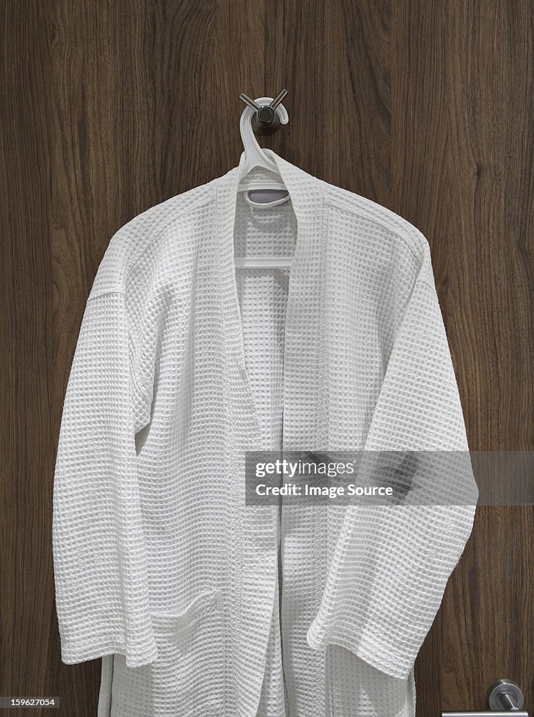 White bathrobe hanging on door