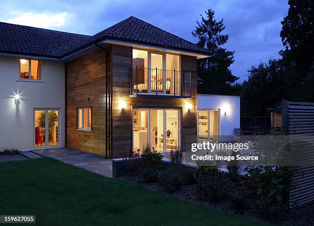 large house illuminated in the evening - terrassentüre stock-fotos und bilder