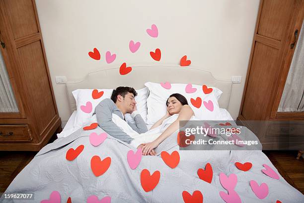 couple in bed with heart shapes on bedclothes - obsessão imagens e fotografias de stock