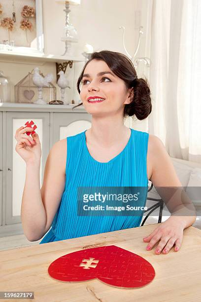 woman doing heart shaped jigsaw puzzle holding piece - lastra a signa stock pictures, royalty-free photos & images