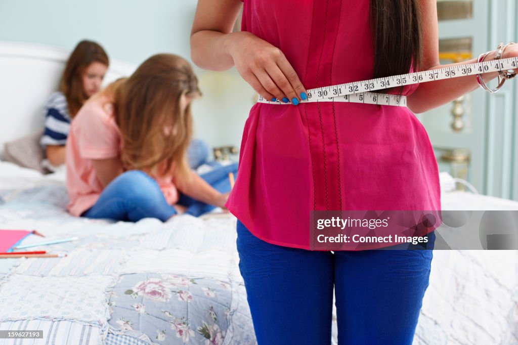 Teenage girl measuring her waist