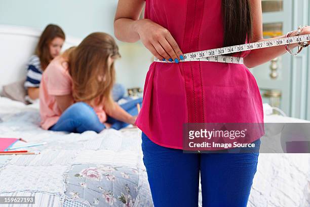 teenage girl measuring her waist - anorexia nervosa stock pictures, royalty-free photos & images