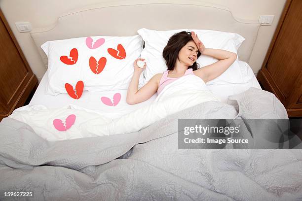 woman crying in bed with broken heart shapes on bedclothes - lastra a signa stock pictures, royalty-free photos & images