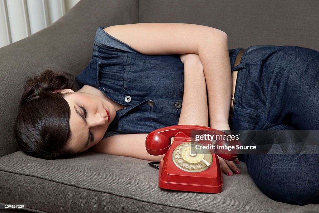 Woman lying on sofa with telephone