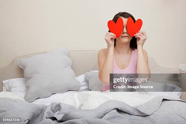 woman in bed holding heart shapes over eyes - lastra a signa stock pictures, royalty-free photos & images