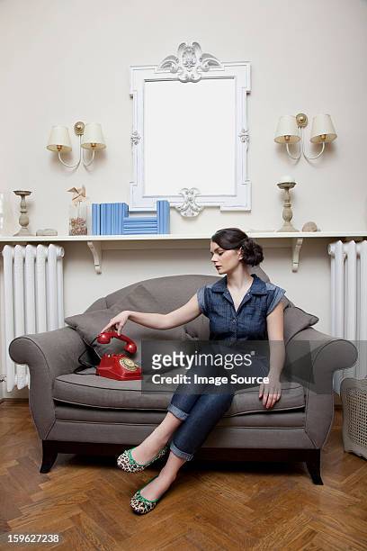 woman on sofa picking up telephone handset - lastra a signa stock pictures, royalty-free photos & images