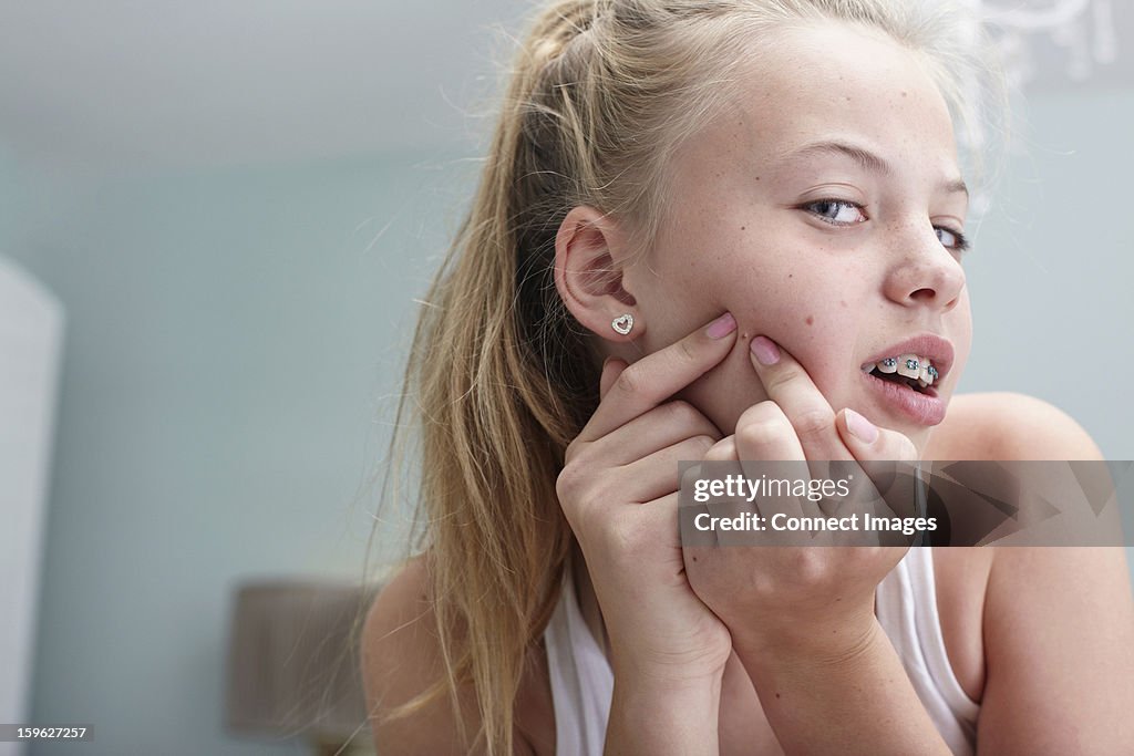 Teenage girl squeezing a spot