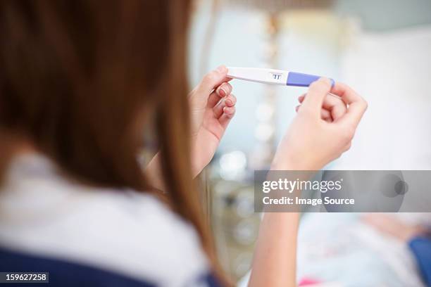 girl holding a pregnancy test - tienerzwangerschap stockfoto's en -beelden