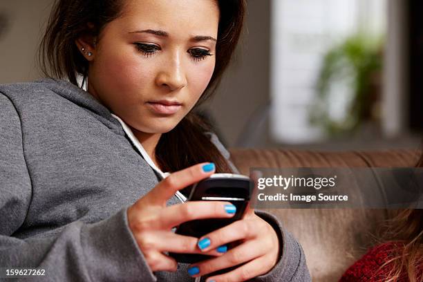 teenage girl looking at cellphone - cyberbullying stockfoto's en -beelden