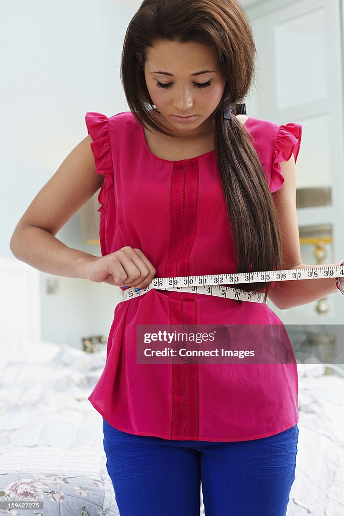 Teenage girl measuring her waist