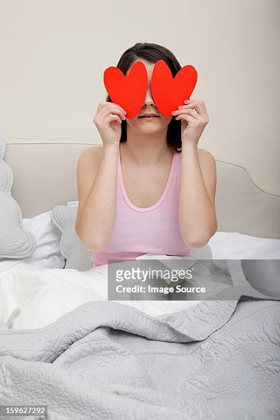 woman in bed holding heart shapes over eyes - lastra a signa stock pictures, royalty-free photos & images