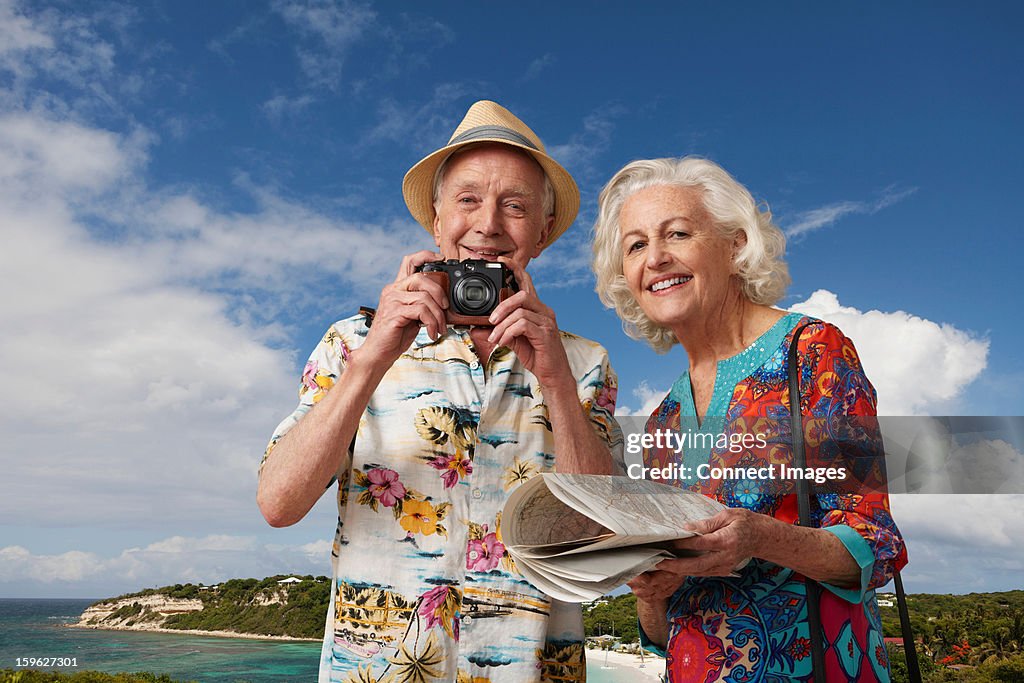 Senior tourist couple with camera and map