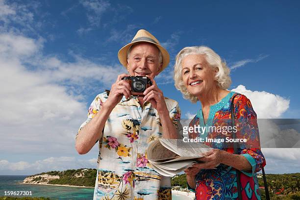 senior tourist couple with camera and map - stereotypical stock pictures, royalty-free photos & images