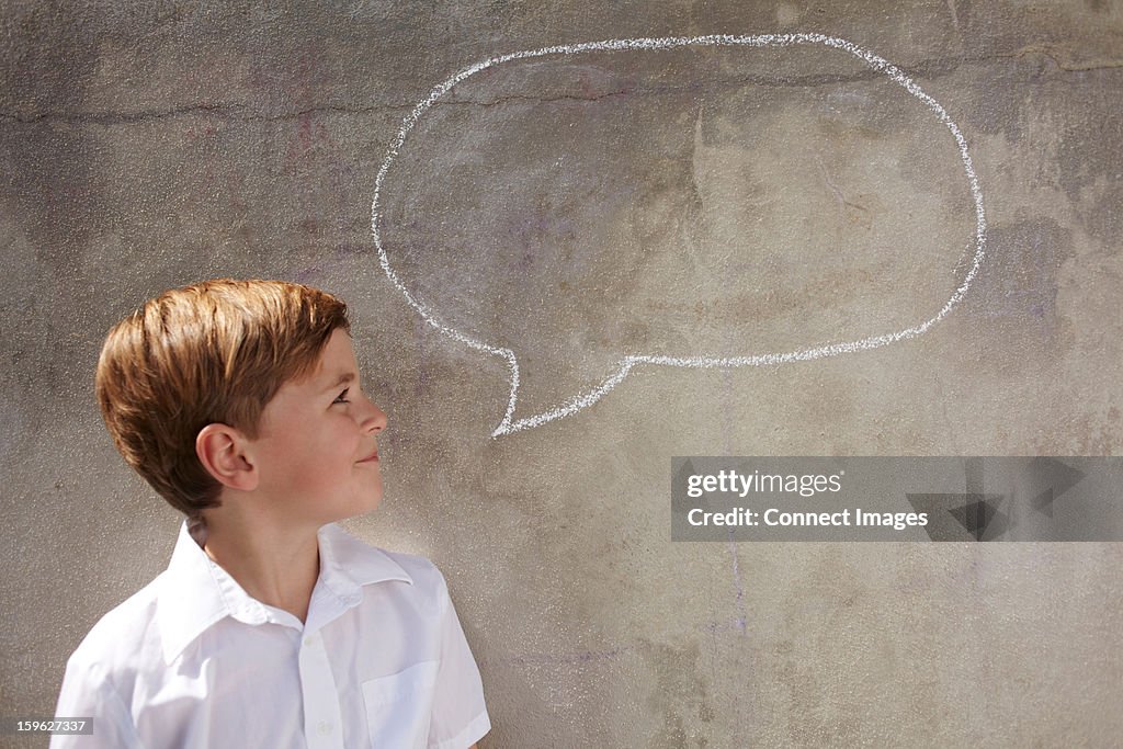 Boy with chalk speech bubble on wall