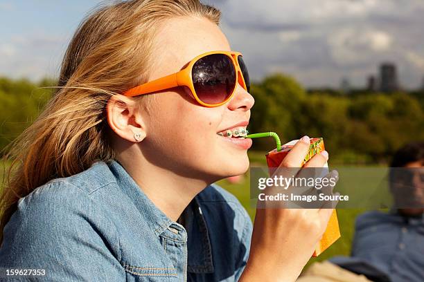 teenage girl in sunglasses drinking from juice carton - boisson en brique photos et images de collection