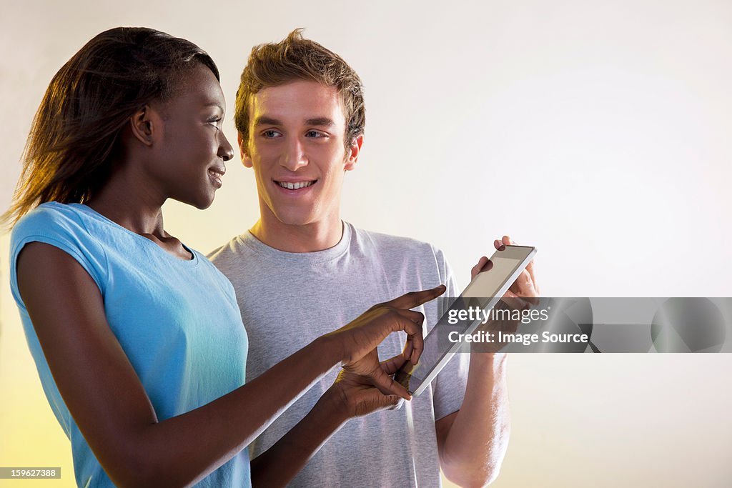 Teenage girl and young man using digital tablet