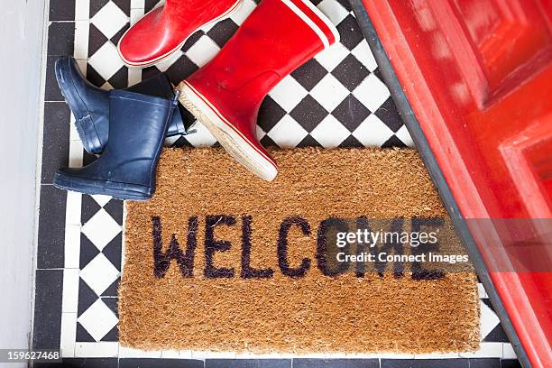 welcome mat and wellington boots - zerbino foto e immagini stock