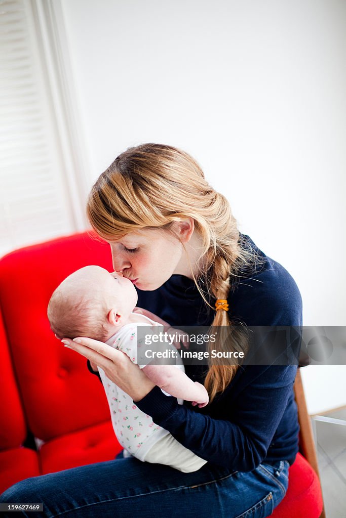 Mother kissing newborn daughter