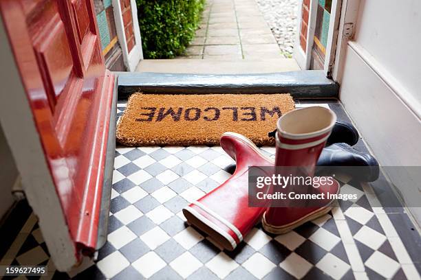 welcome mat and wellington boots - rote schuhe stock-fotos und bilder