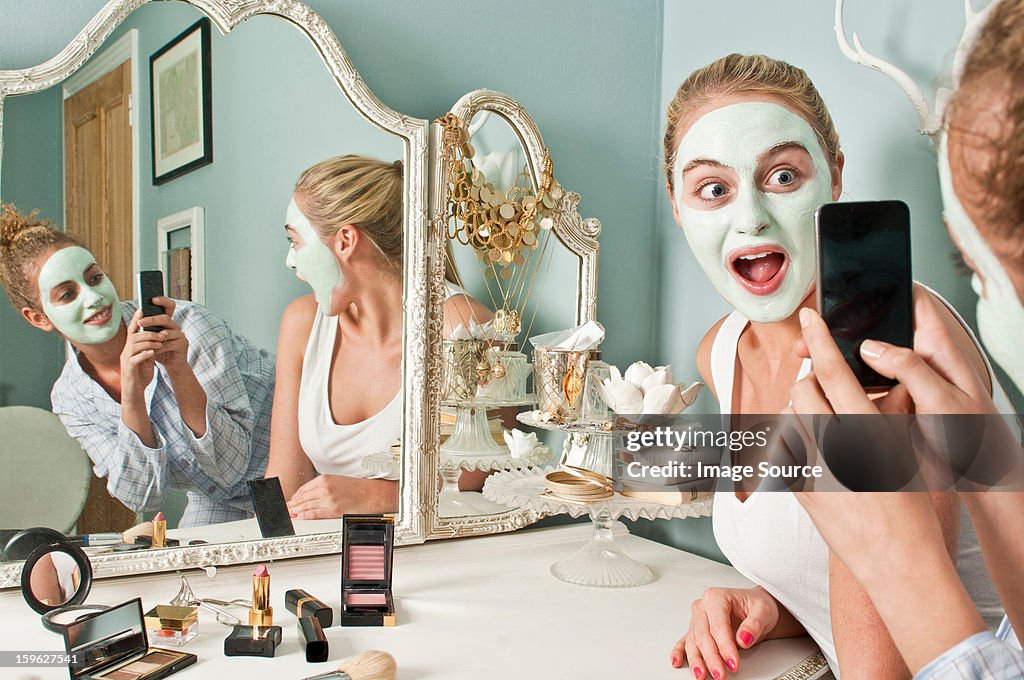 Woman wearing face mask being photographed by friend