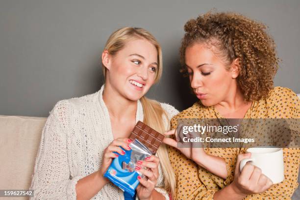 woman offering friend chocolate - eating chocolate stock pictures, royalty-free photos & images