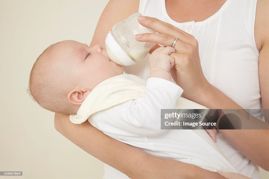 Mother feeding newborn baby bottle of baby milk