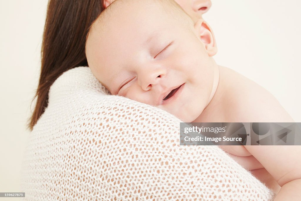 Mother with newborn baby sleeping on shoulder