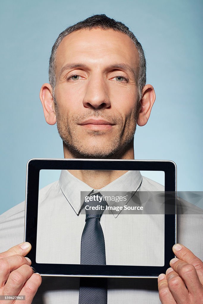 Man covering neck with digital tablet