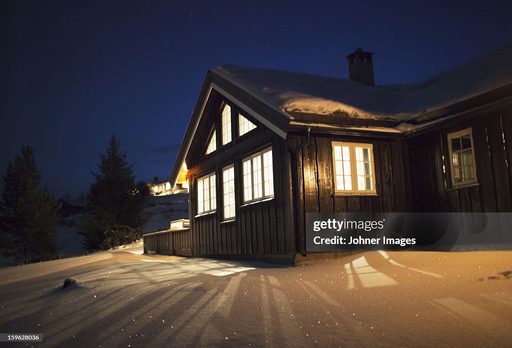 Wooden cabin in snow at night