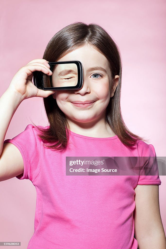 Girl holding smartphone over eye