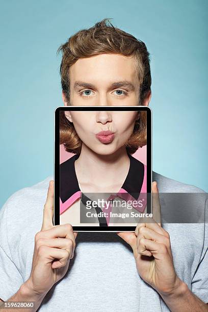 man covering half his face with digital tablet, with womans mouth - men doing quirky things stock-fotos und bilder