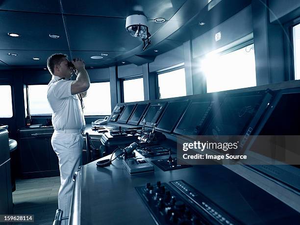 captain in cockpit of motor yacht, using binoculars - ship captain stock pictures, royalty-free photos & images