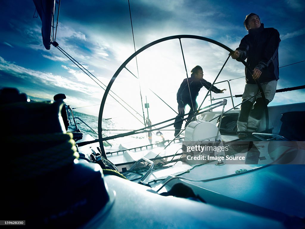 Sailors steering yacht