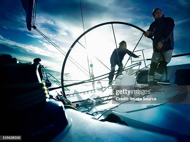 Sailors steering yacht