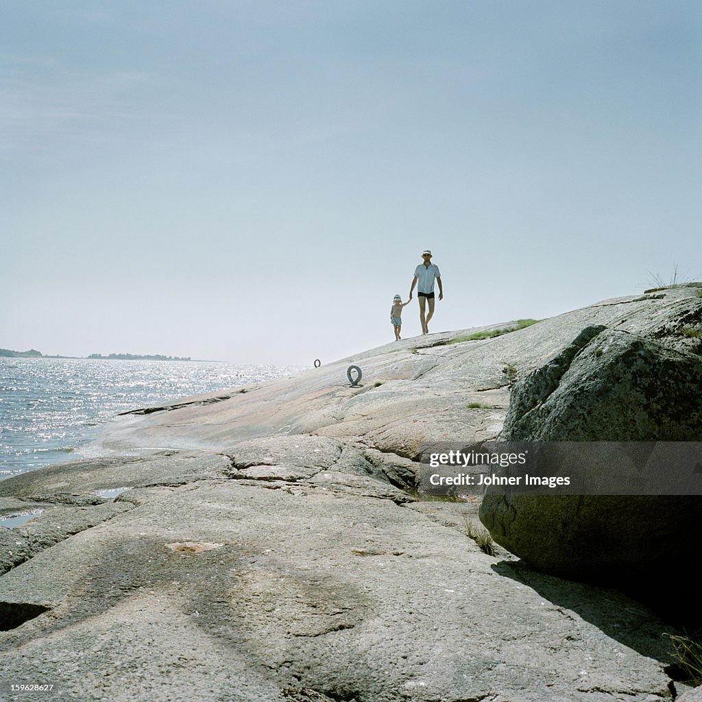 Father and daughter walking on cliffs, Blekinge, Sweden.