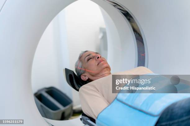 mature woman lying down on a cat scan machine with eyes closed at the hospital - cat scan 個照片及圖片檔