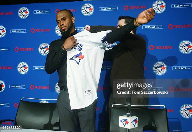 Jose Reyes of the Toronto Blue Jays puts on his jersey before being introduced at a press conference with general manager Alex Anthopoulos at Rogers...