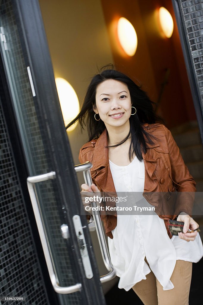Portrait of a mid adult woman exiting through glass door