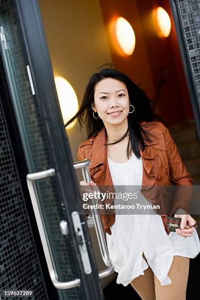 portrait of a mid adult woman exiting through glass door - farewell in 2012 stock pictures, royalty-free photos & images