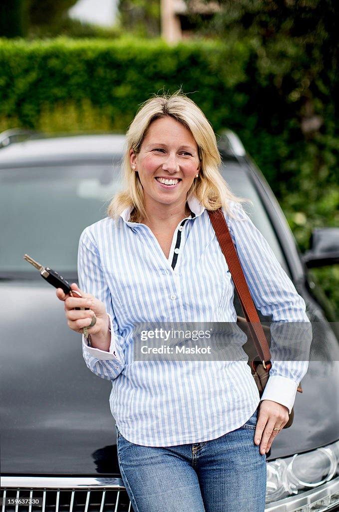 Mid adult woman holding keys in front of her car