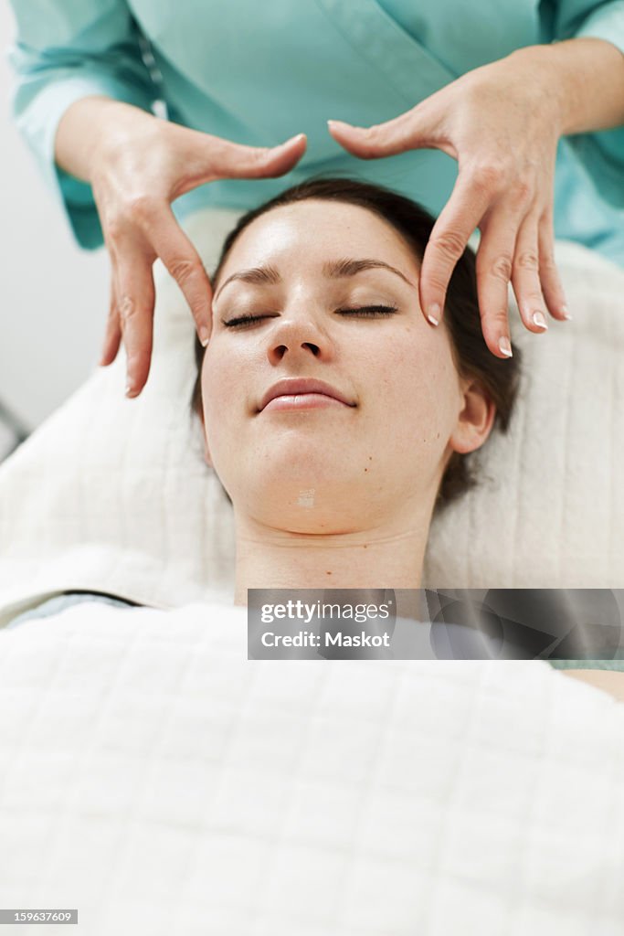 Young woman receiving face massage from masseur at beauty spa