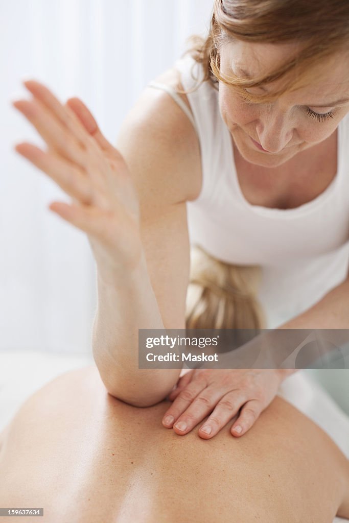 Mature therapist massaging mid adult woman's back with elbow