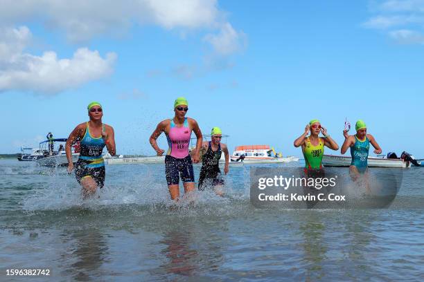 Fenella Wightman of Team Bermuda runs out of the water with Katie Pattie of Team Fiji, Chloe Rossouw of Team Namibia, Erin Pritchard of Team Bahamas...