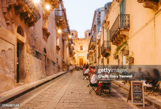 people dining outside restaurants and bars at dusk in noto - sicilië stockfoto's en -beelden