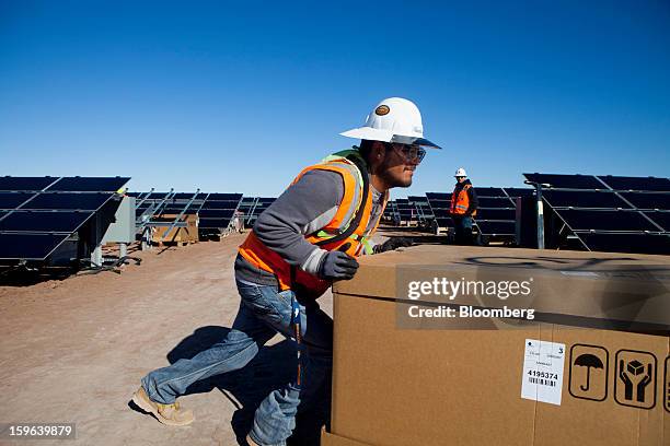 Contractor for First Solar Inc. Pushes a box of materials during construction of the Tenaska Imperial Solar Energy Center South project in Imperial...