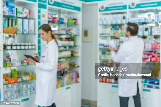 pharmacist in uniform arranges products on shelves in pharmacy./out of focus - lagförslag bildbanksfoton och bilder