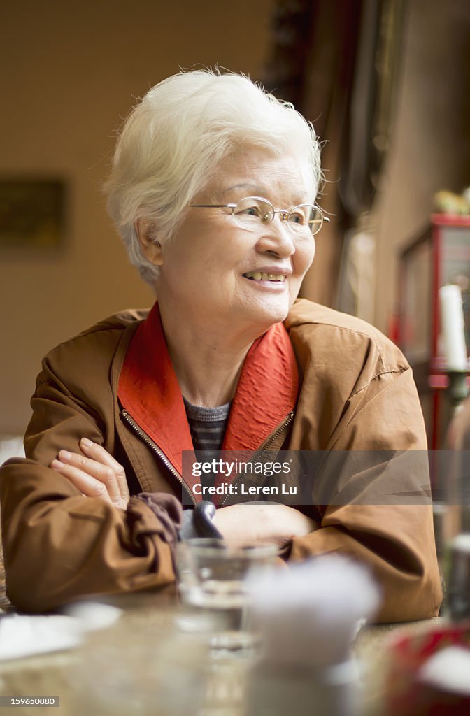 Senior woman sits behind a table